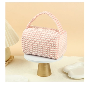 Close-up of pink checkered waffled fabric cosmetic bag on a white display stand
