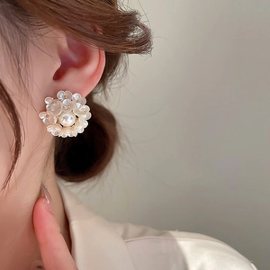 Macro detail of floral pearl earrings featuring shell texture petals and gold metal base