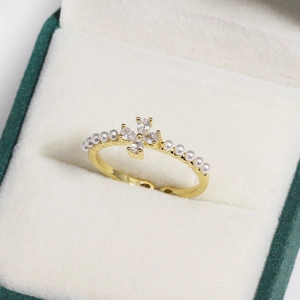 Detail of adjustable gold ring with floral zircon clusters and side pearl accents