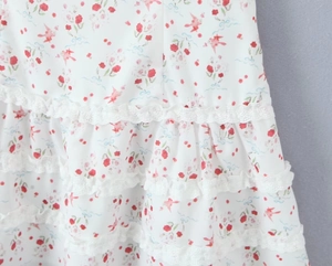 Detalle de vestido con estampado floral y aves, encaje blanco y volantes en capas