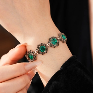 Close-up of vintage flower bracelet with green crystals and grey rhinestones in silver finish