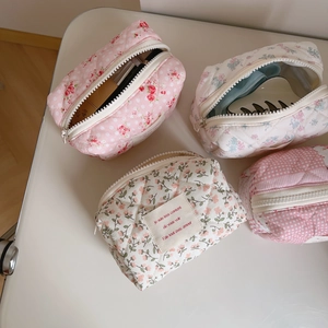 Macro detail of quilted floral makeup bags showing cotton texture and zipper closure