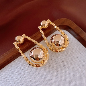 Close-up of gold-plated spherical earrings with hammered texture on a fabric tray