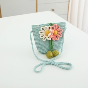 Detail of woven straw shoulder bag with crochet flowers and green pom-pom accents