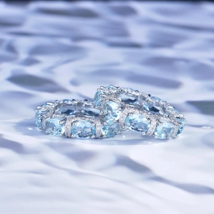 Close-up of silver eternity rings with oval blue gemstones and micro-pave diamond accents