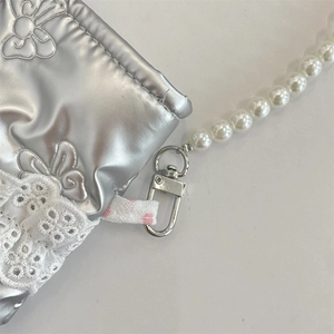 Dettaglio della borsa a tracolla trapuntata argento con pizzo bianco e tracolla di perle