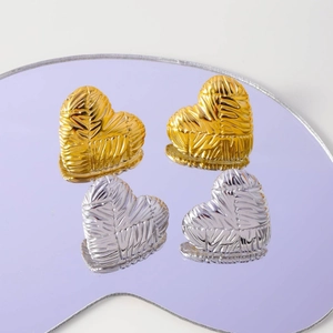 Textured gold and silver heart-shaped earrings with striped metal surface on mirror