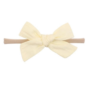 Detail of soft nylon infant headband with a light yellow textured fabric bow on white background