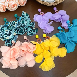 Flat lay of colorful fabric petal earrings in blue, purple, yellow and pink on a wood table