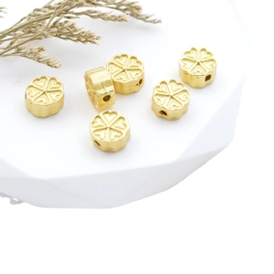 Matte gold flower spacer beads for DIY jewelry on white geometric display stand