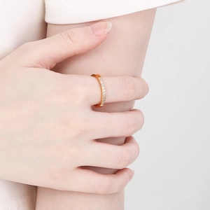 Close-up of minimalist rose gold ring with white crystals on female hand in soft lighting