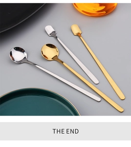 Close-up of gold and silver long-handled stainless steel mixing spoons on a grey surface