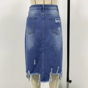 Dettaglio macro della gonna di jeans a vita alta con tasca usurata e orlo a frange