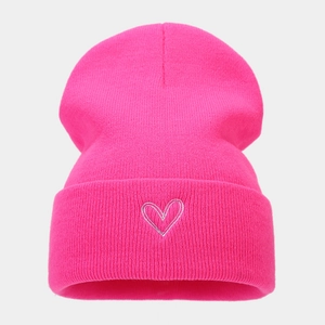 Nahaufnahme einer pinkfarbenen Strickmütze mit silberner Herzstickerei und Rippstrick-Struktur