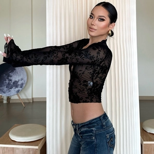 Detail of sheer black floral lace fabric on a long sleeve slim fit cropped top