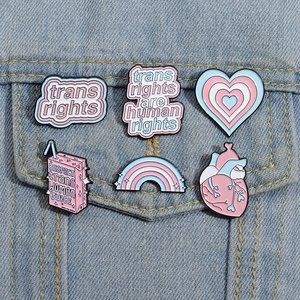 Transgender rights enamel pin set on blue denim jacket featuring heart and rainbow designs
