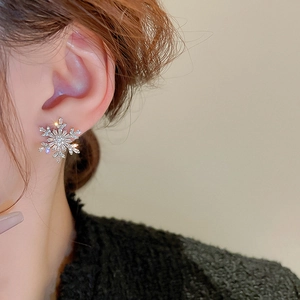 Close-up of sparkling zircon snowflake earrings with faux pearls on model ear