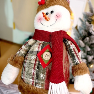 Dettaglio di un pupazzo di neve di peluche con sciarpa di maglia e decori natalizi
