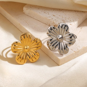 Bagues fleurs minimalistes plaquées or 18 carats et argent sur fond de tissu neutre