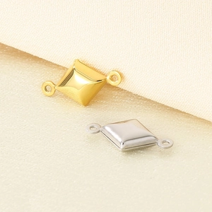 Macro shot of gold and silver diamond-shaped metal connectors on beige fabric