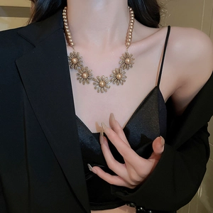 Detailed view of a gold floral necklace featuring pearls and sparkling rhinestones