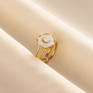 Minimalist gold stainless steel open ring with white enamel moon relief on cream fabric