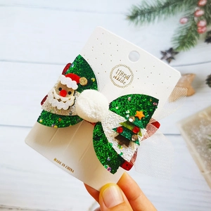 Christmas green glitter bow hair clip with Santa Claus and tree on festive background