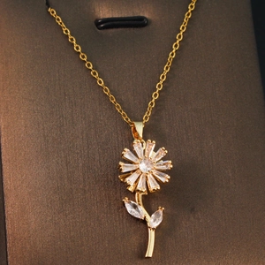 Close-up of golden necklace featuring a floral pendant with clear zircon gemstones