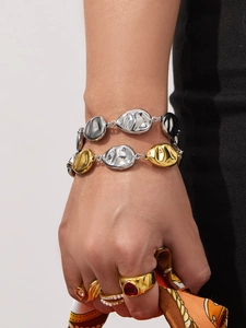 Detail of layered gold and silver chain bracelet with textured irregular metal links