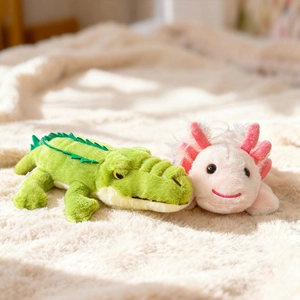 Cute plush crocodile and pink axolotl stuffed animals lying on a soft white blanket