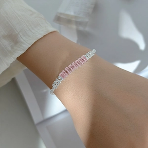 Close-up of silver bracelet featuring pink rectangular gemstones and white cubic zirconia