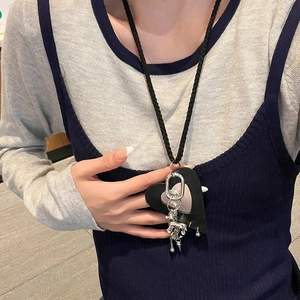 Detail of bohemian black heart pendant necklace with silver metal charms and safety pins