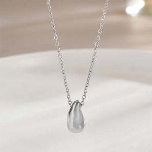 Gros plan détaillé d'un pendentif goutte d'argent avec finition polie sur une chaîne fine