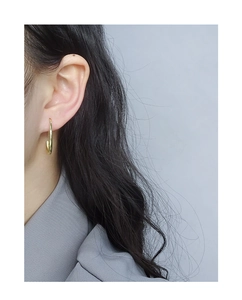 Vista laterale di modella con orecchini a forma di U in argento dorato minimalista