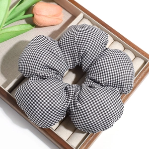 Detailed view of a black and white gingham oversized floral scrunchie on a display tray