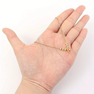 Minimalist gold letter A necklace with round beads on a delicate chain in palm view