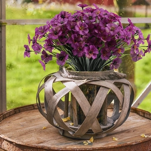 Close-up of artificial purple violet silk flowers in a rustic woven wooden basket