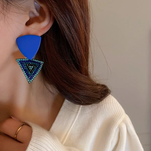 Macro view of blue geometric triangle earrings featuring emerald green rhinestones