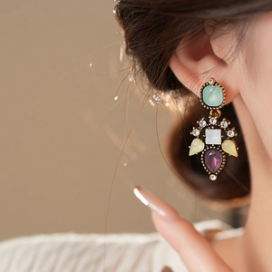 Detailed macro view of colorful gemstone drop earrings featuring vintage floral metalwork
