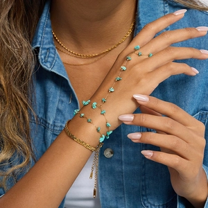 Detailed close-up of a gold ring-to-wrist hand chain set with natural turquoise stones