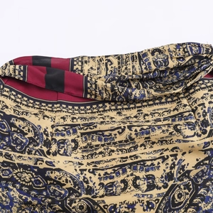 Macro detail of intricate paisley pattern and stitching on a burgundy floral wrap skirt