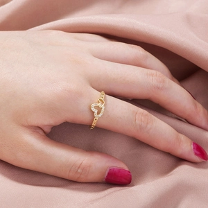 Fashionable gold-plated hollow double heart ring with zircon stones on pink silk background