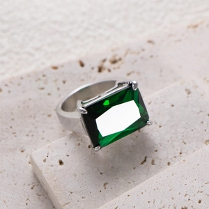 Detailed macro view of an emerald-cut green gemstone set in a silver titanium ring