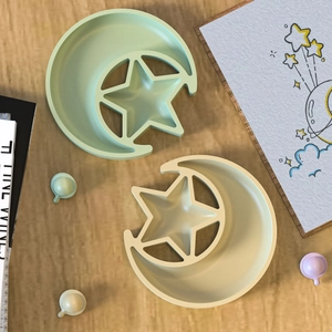 Overhead view of moon and star shaped silicone storage trays on a wooden background