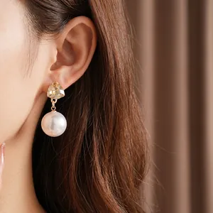Elegant gold triangle rhinestone and white pearl drop earrings on a model