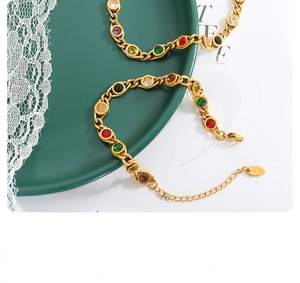 Detail of colorful zircon gold chain bracelet with K18 tag on green ceramic plate