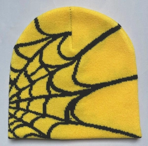 Close-up of yellow knitted beanie showing detailed black spider web jacquard patterns