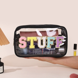 Transparent PVC toiletry bag with STUFF glitter letters and black zipper held by hand