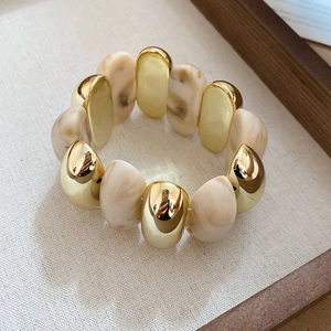 Detailed close-up of amber acrylic marble beads and polished gold metal bracelet