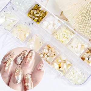 Macro detail of 12-grid nail art box with thin iridescent natural shell flakes for manicure